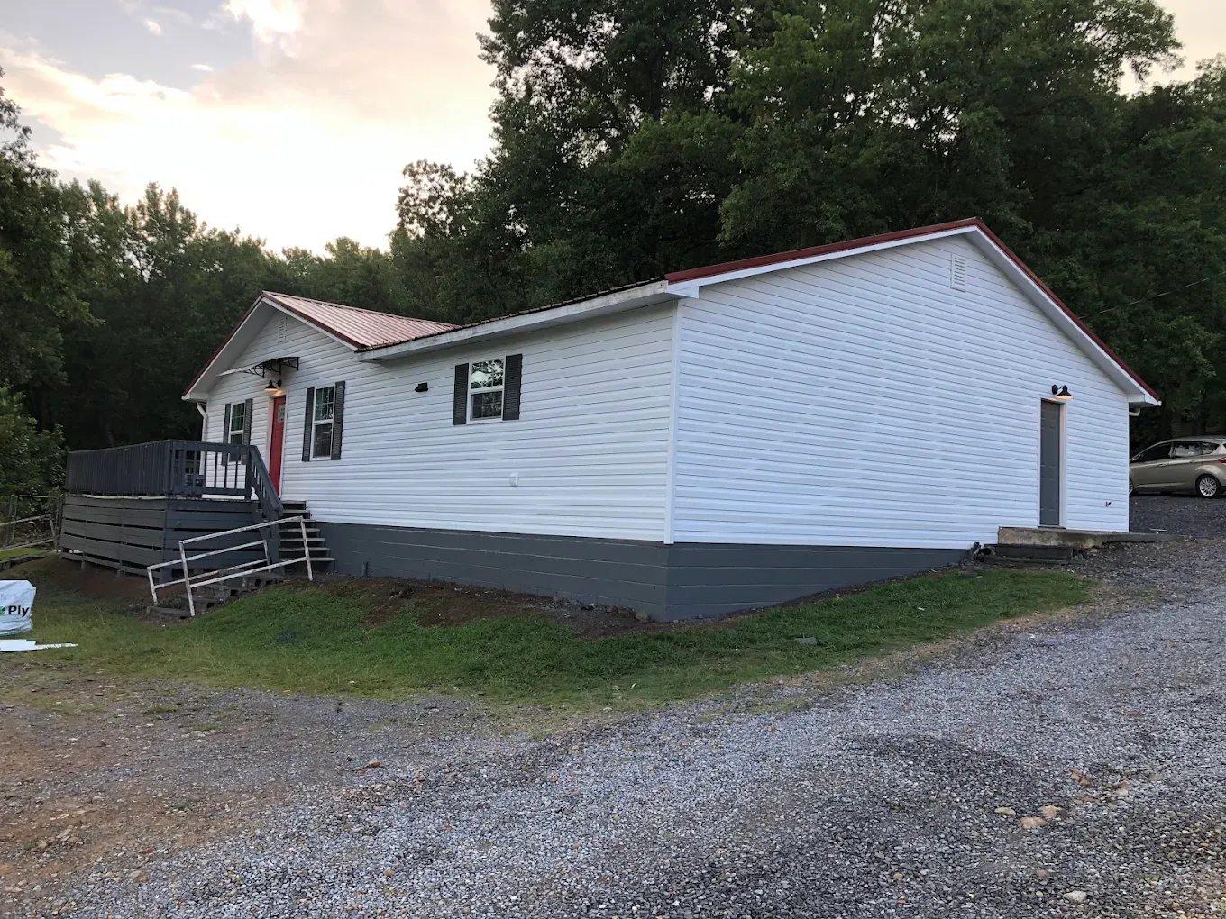 Team Farrell home with new siding and a red metal roof at sunset